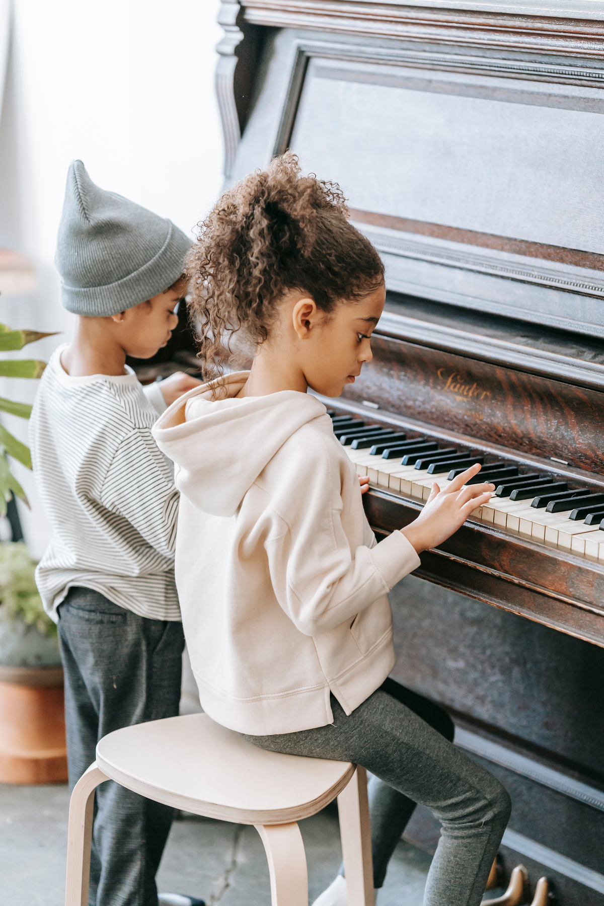 Focused black children playing piano together at home